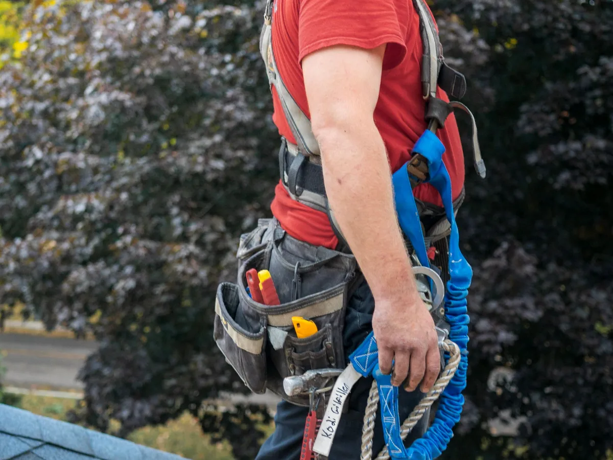 Roofer in a safety harness working near a chimney