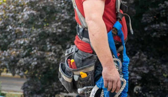 Roofer in a safety harness working near a chimney