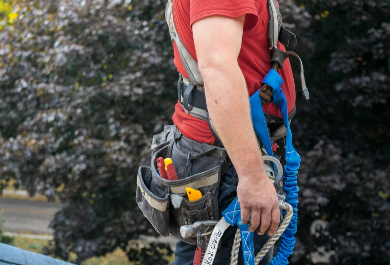 Roofer in a safety harness working near a chimney