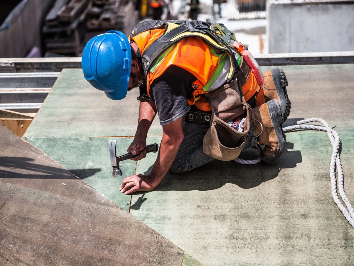 Roofer in safety harness installing roof sheathing
